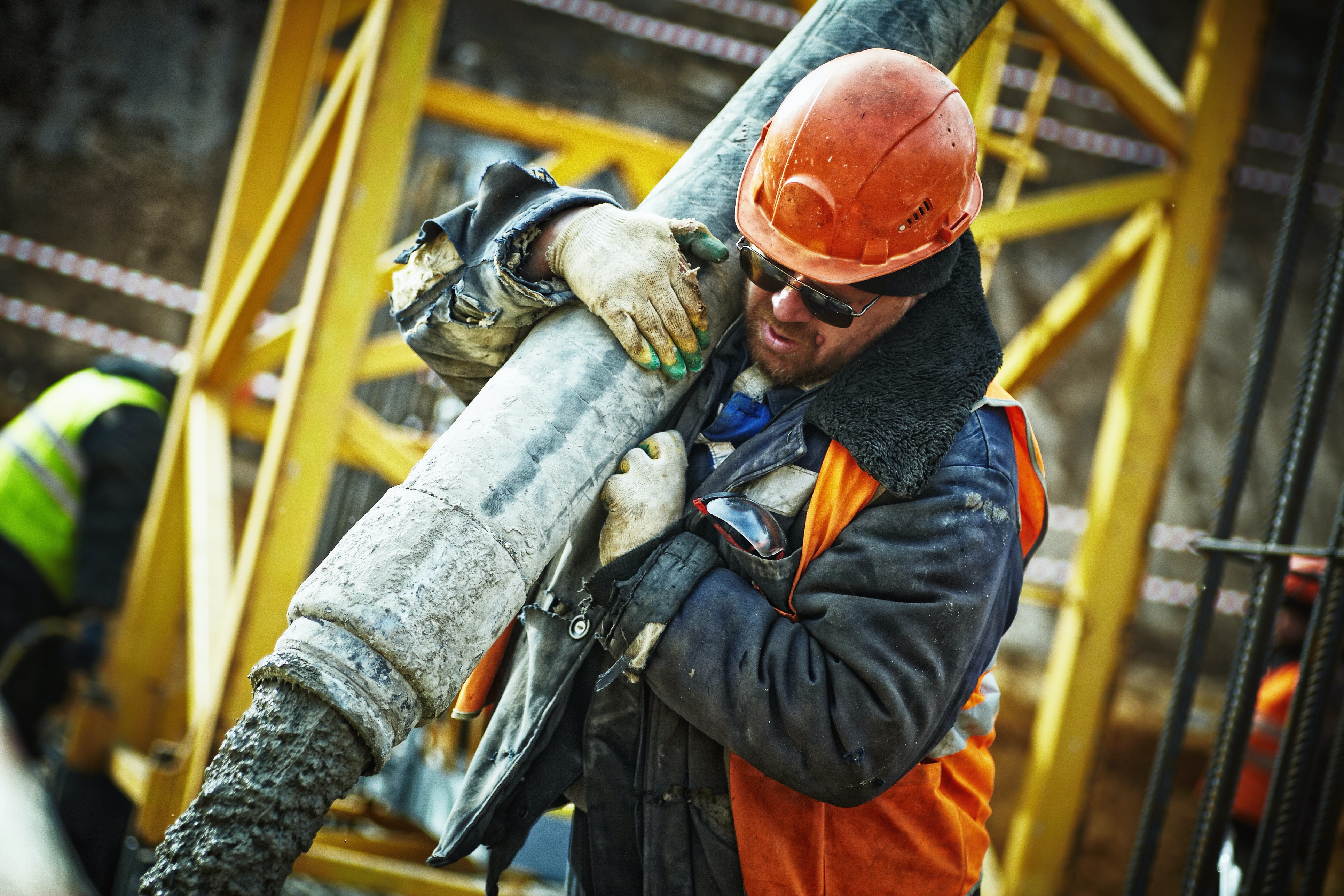 Construction worker carrying a gray pipe